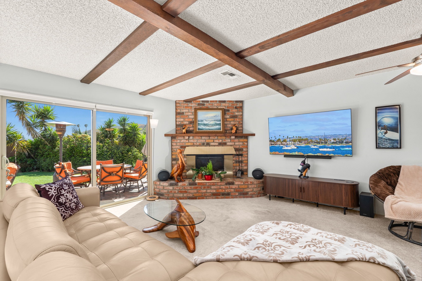 Your spacious living room features exposed beams, a brick fireplace, and expansive windows overlooking tropical gardens.