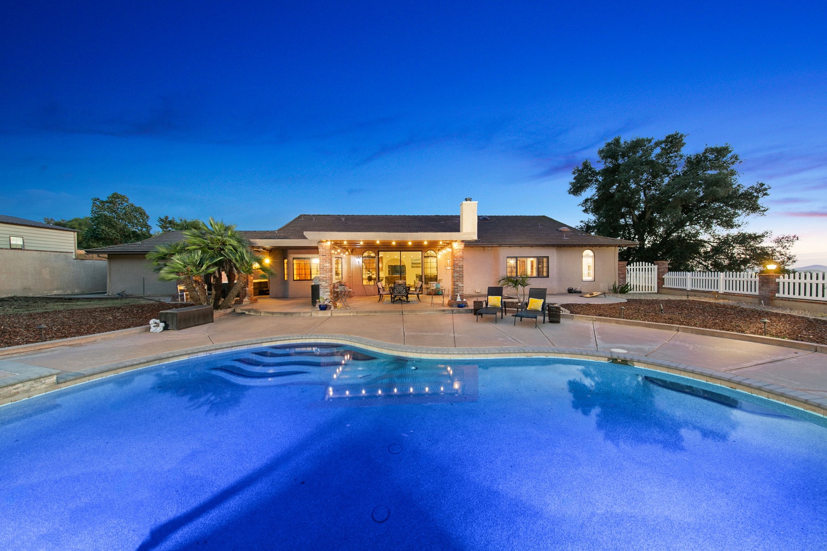 Stunning private retreat with sparkling pool and beautifully lit outdoor living space, perfect for evening relaxation under the stars.