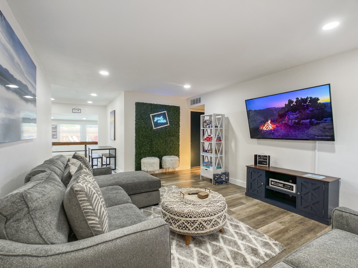 Comfortable living room with sofas, Flat screen tv connected to streaming services, foosball table, shuffleboard table, and arcade game!