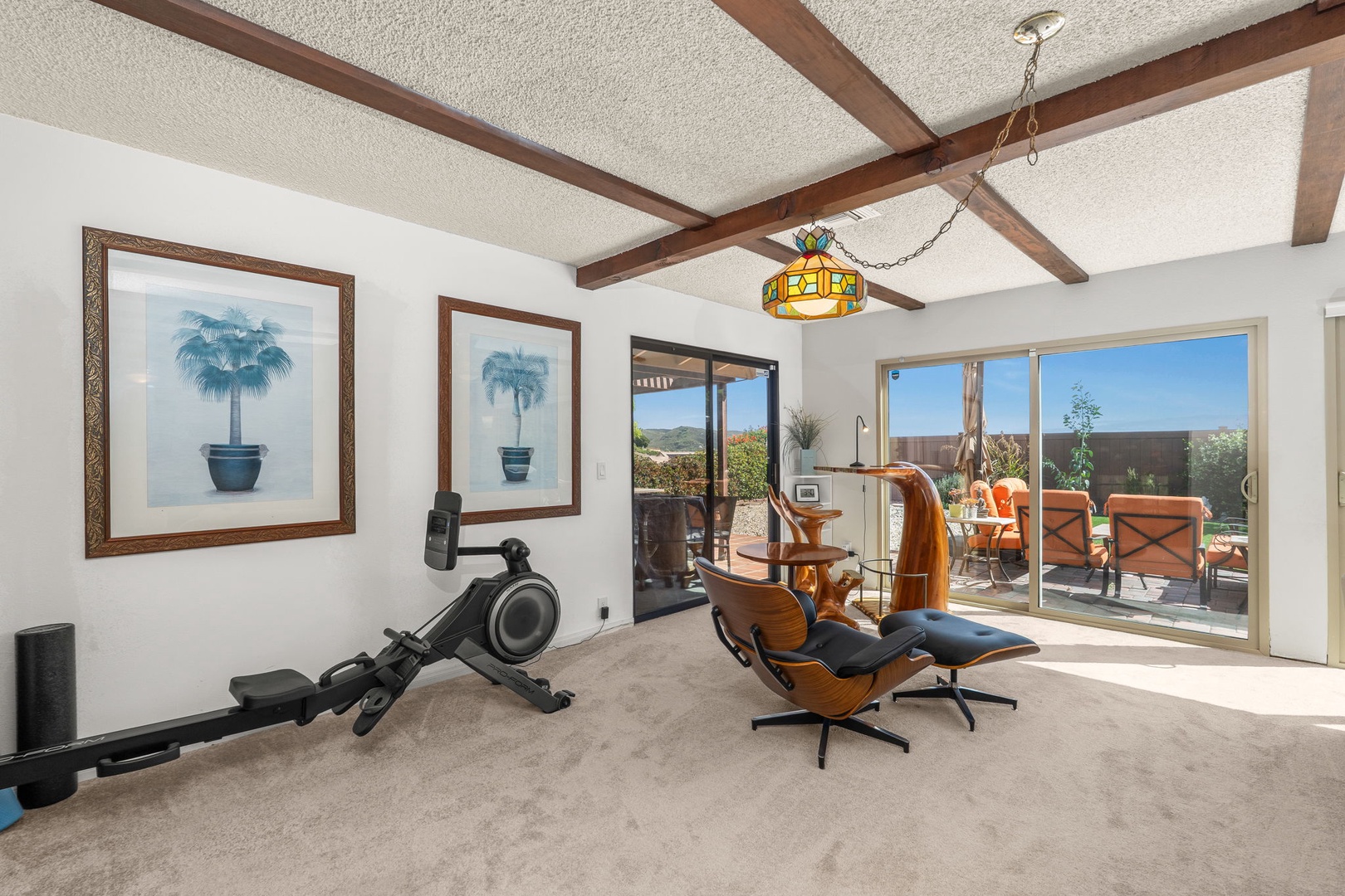 Stay active in your private fitness space with exposed beams and patio views, featuring modern equipment in a warm, inviting atmosphere.