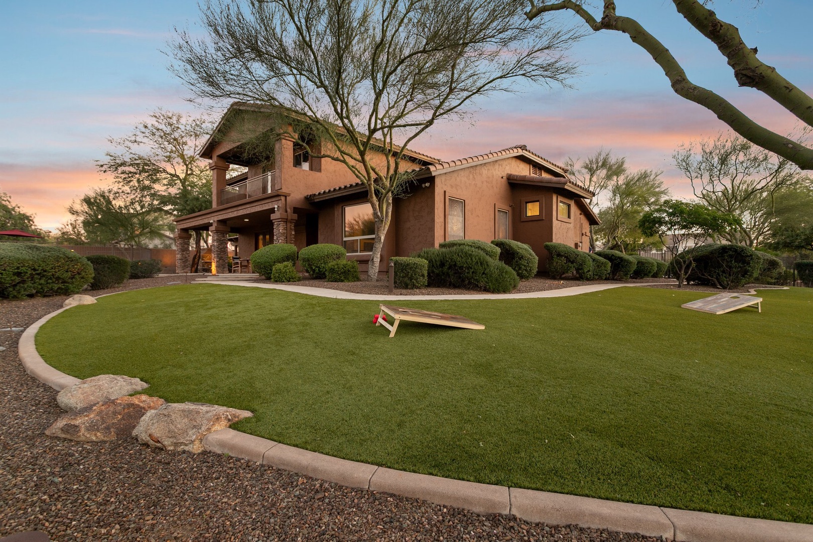 Desert contemporary home features manicured grounds with mature trees and spacious yard perfect for outdoor gatherings.