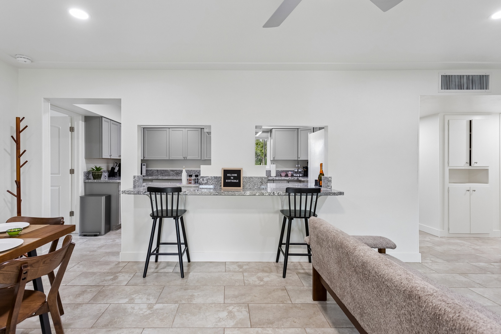 Step into your bright, open living space where a sleek granite breakfast bar invites you to enjoy morning coffee or casual meals. Cool tile flooring and fresh white walls create a breezy, relaxed vibe perfect for unwinding after a day of exploring.