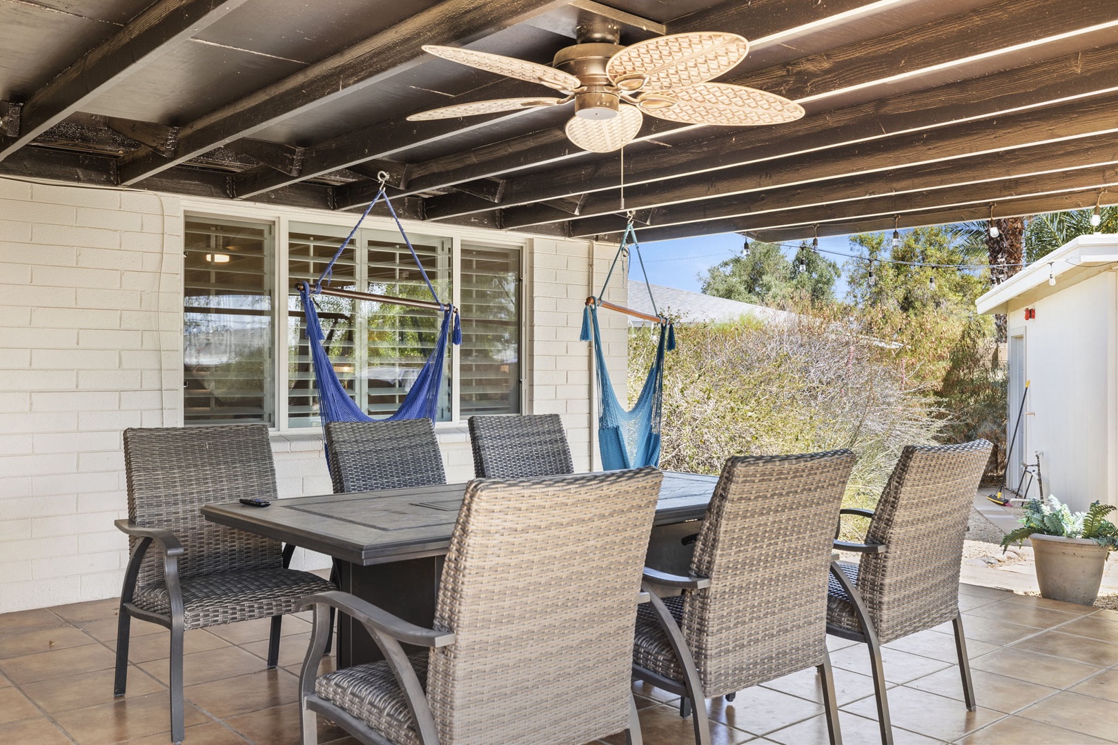 Outdoor lounge with hanging hammock chairs, fire pit table, and Flat Screen TV