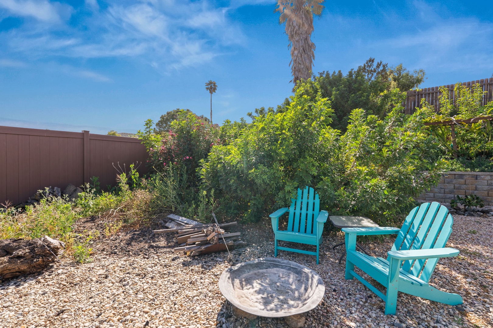 Relax in bright turquoise Adirondack chairs around your private fire pit, surrounded by lush desert landscaping under endless blue skies.