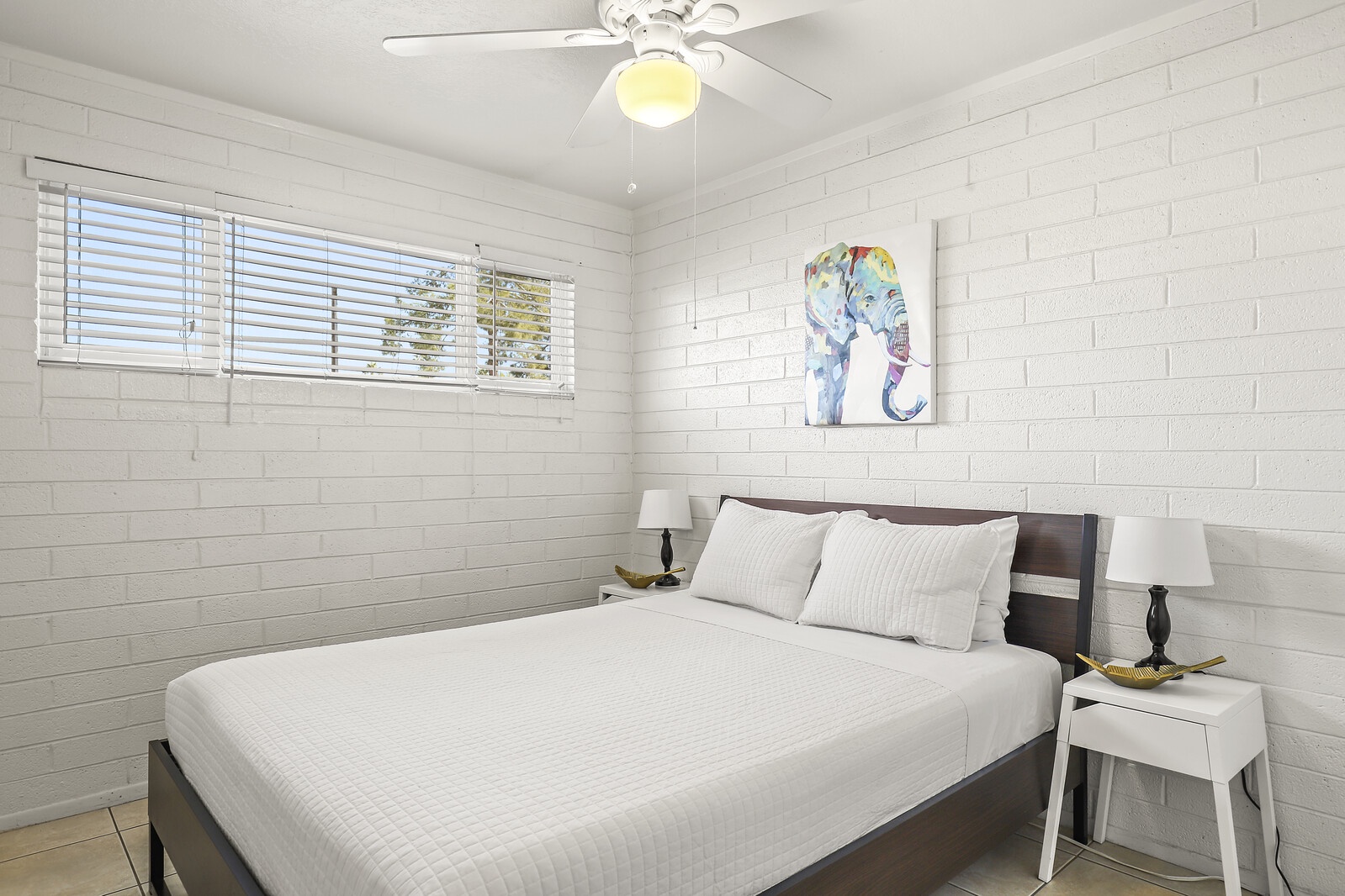 One bedroom with a queen size bed covered in comfortable and clean white linens.