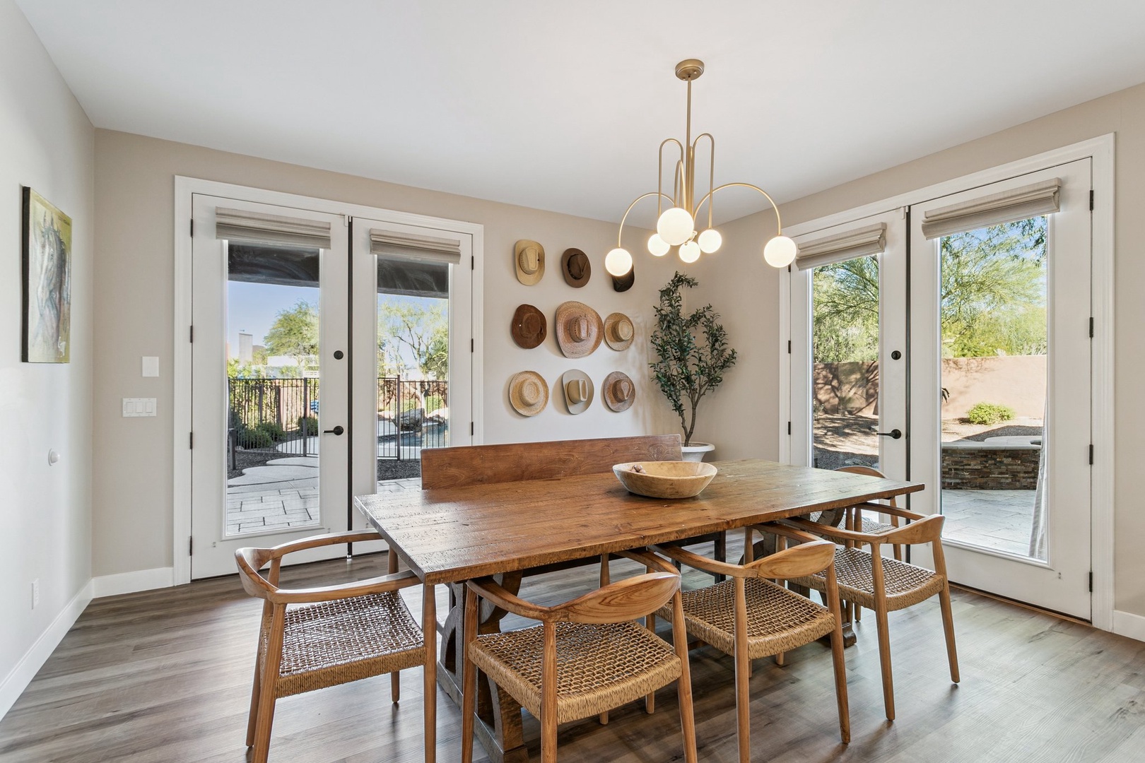 Gather around your beautiful dining table with modern chandelier lighting, where warm wood tones and woven chairs create the perfect setting for memorable meals together.