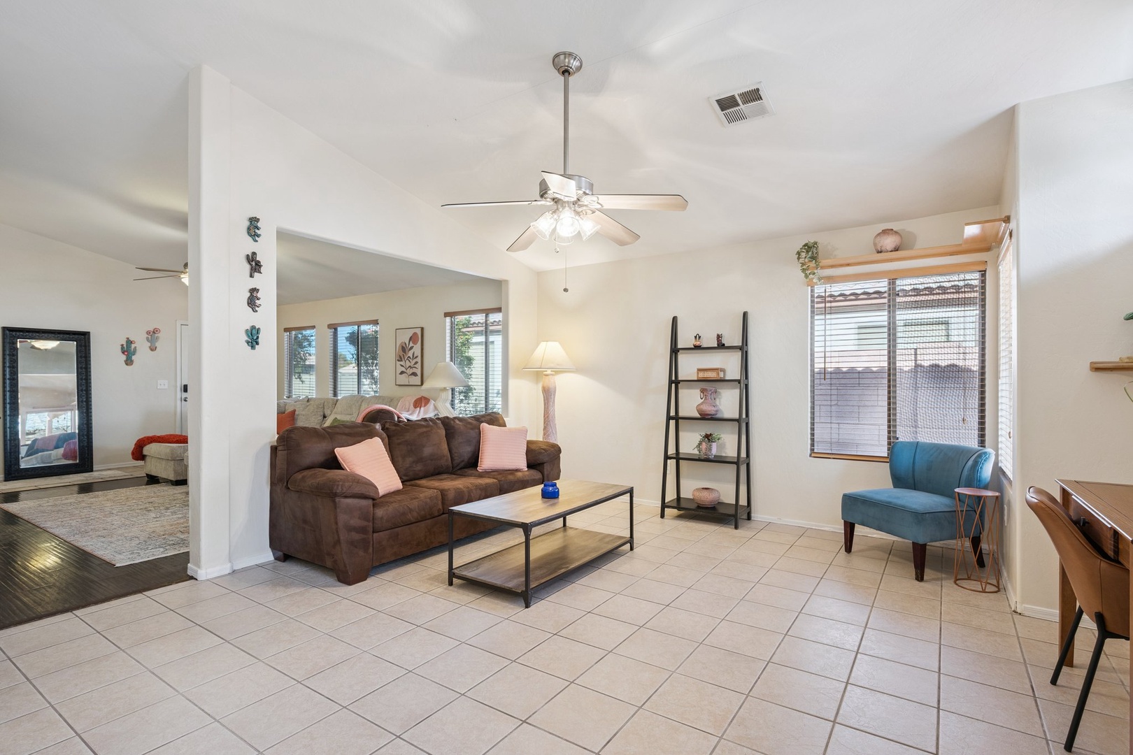 Relax in your spacious open living area with comfortable seating, ceiling fan, and plenty of natural light streaming through large windows.