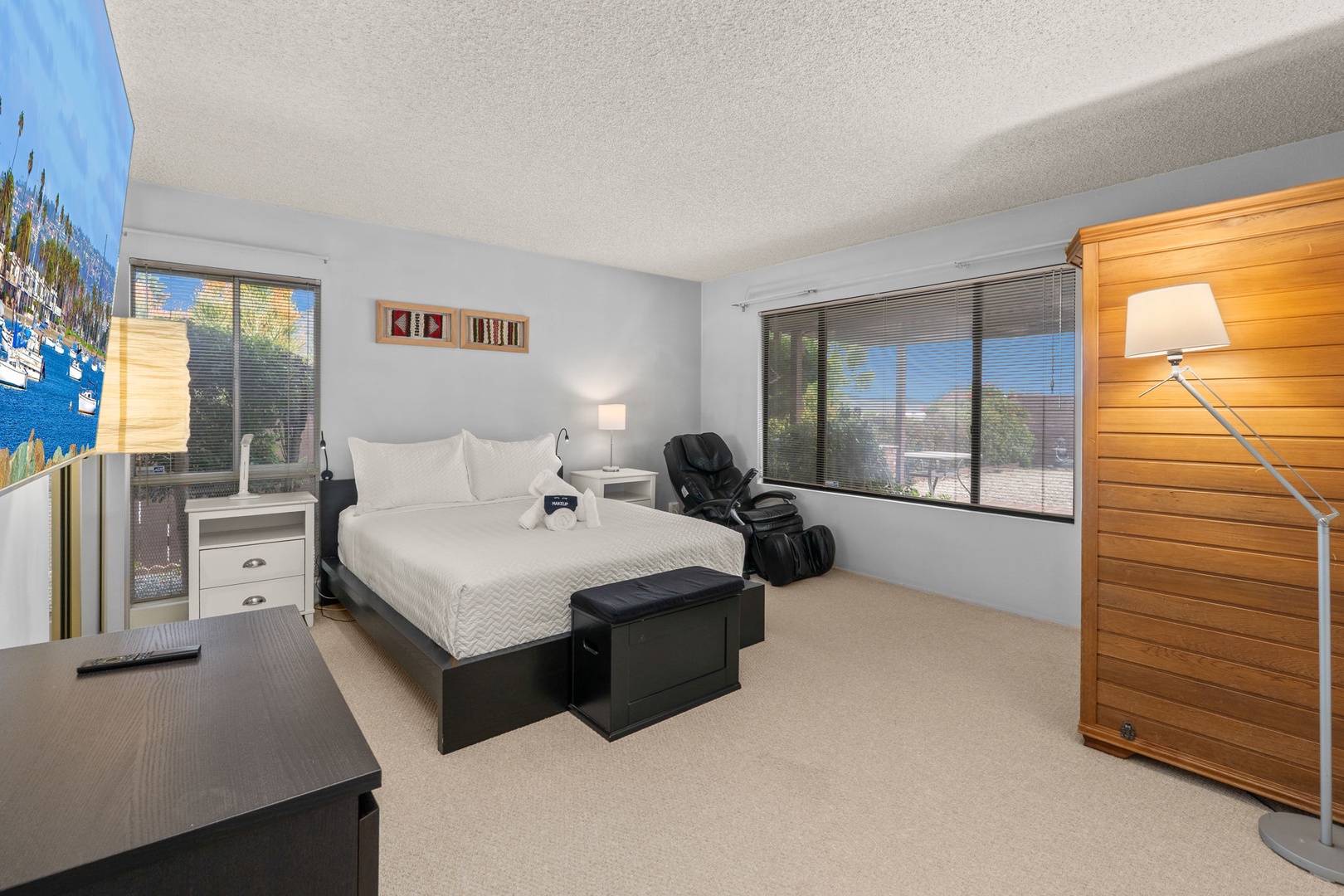 Unwind in your spacious bedroom featuring a plush queen bed, relaxing massage chair, and warm wood accents creating the perfect retreat.