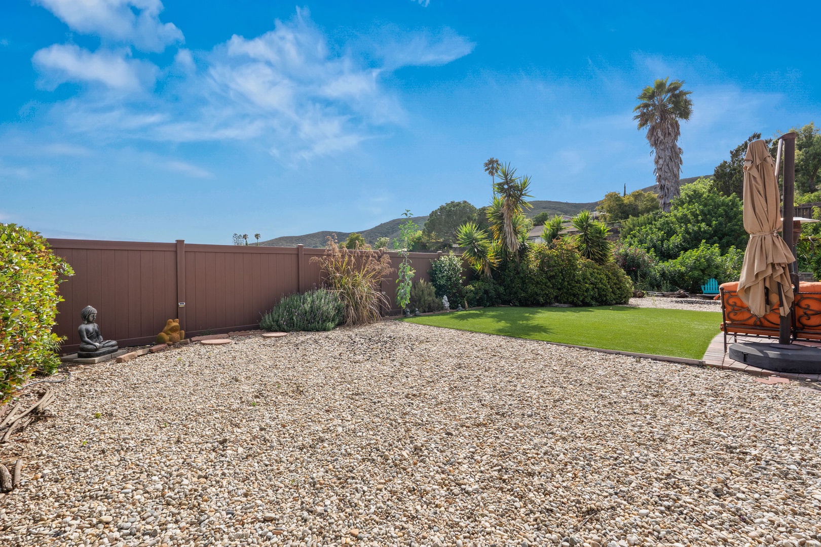 Relax in your private backyard oasis with lush lawn, zen garden, and mountain views under endless blue skies.