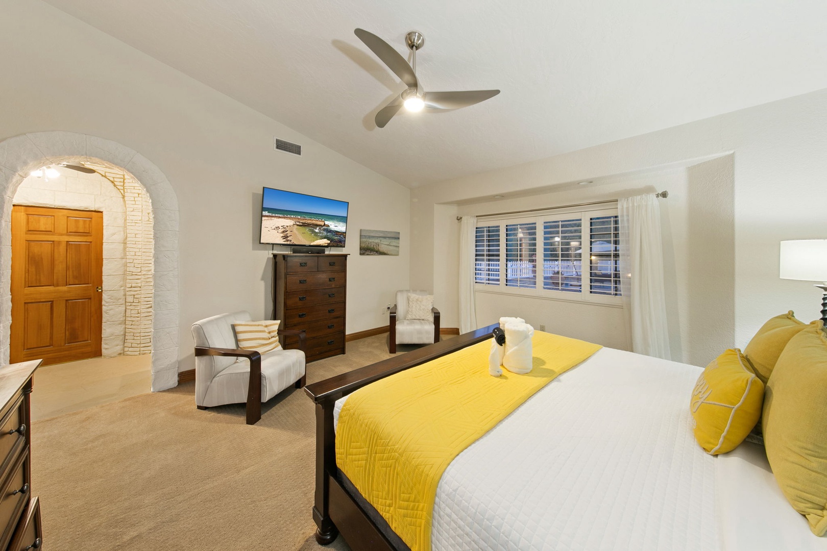 Unwind in your elegant primary suite featuring a plush king bed, cozy seating area, TV, and ensuite bathroom.