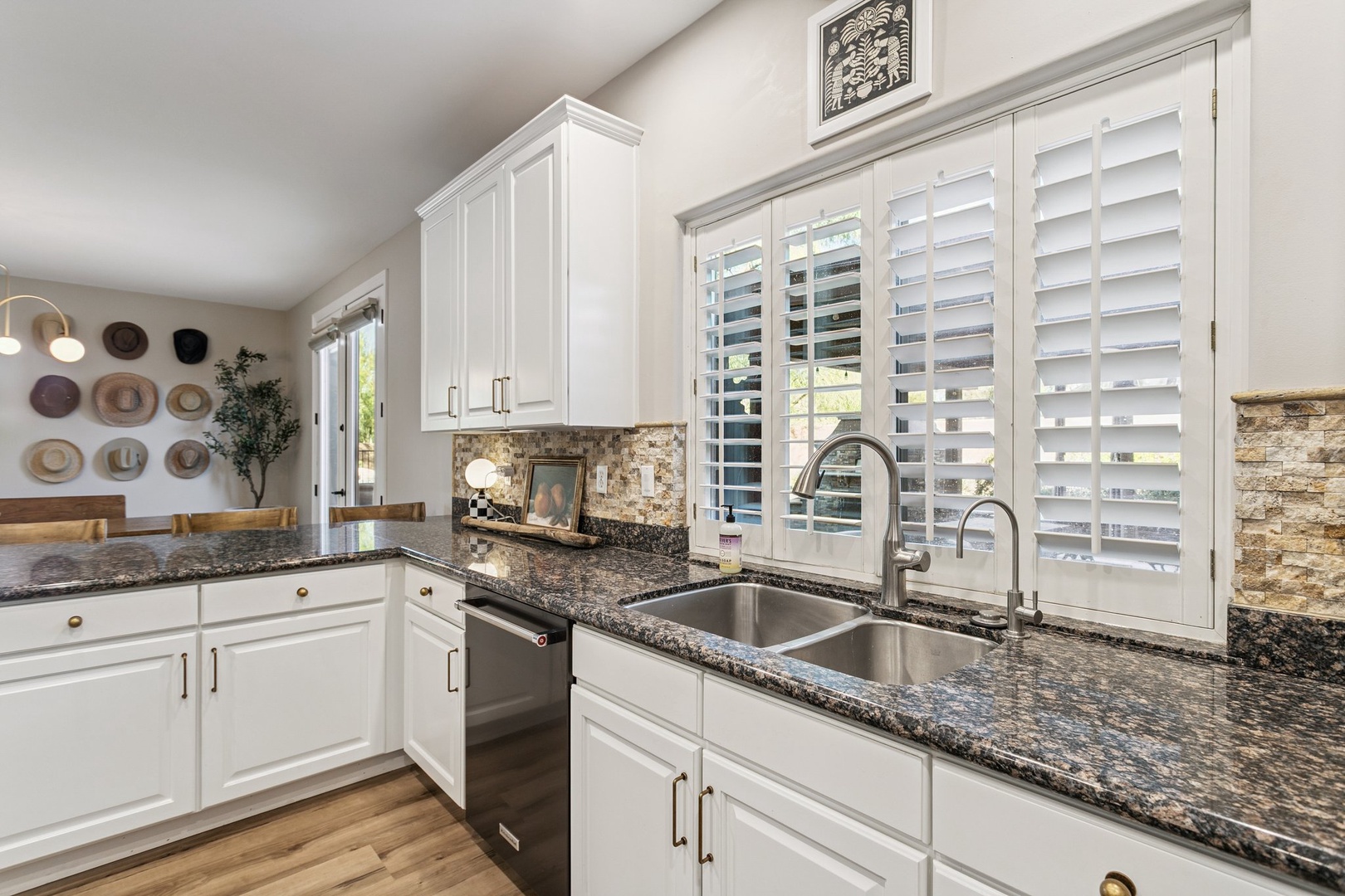 Your gourmet kitchen awaits with granite counters, stainless appliances, and charming plantation shutters filtering natural light.
