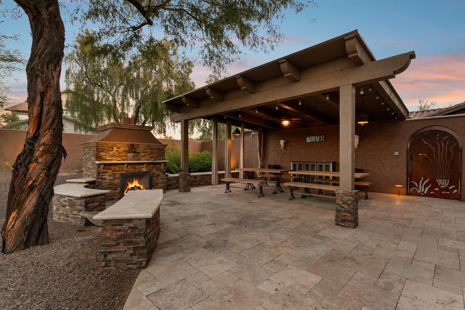 Spacious covered outdoor pavilion with fireplace, dining area, and evening ambiance for memorable gatherings.