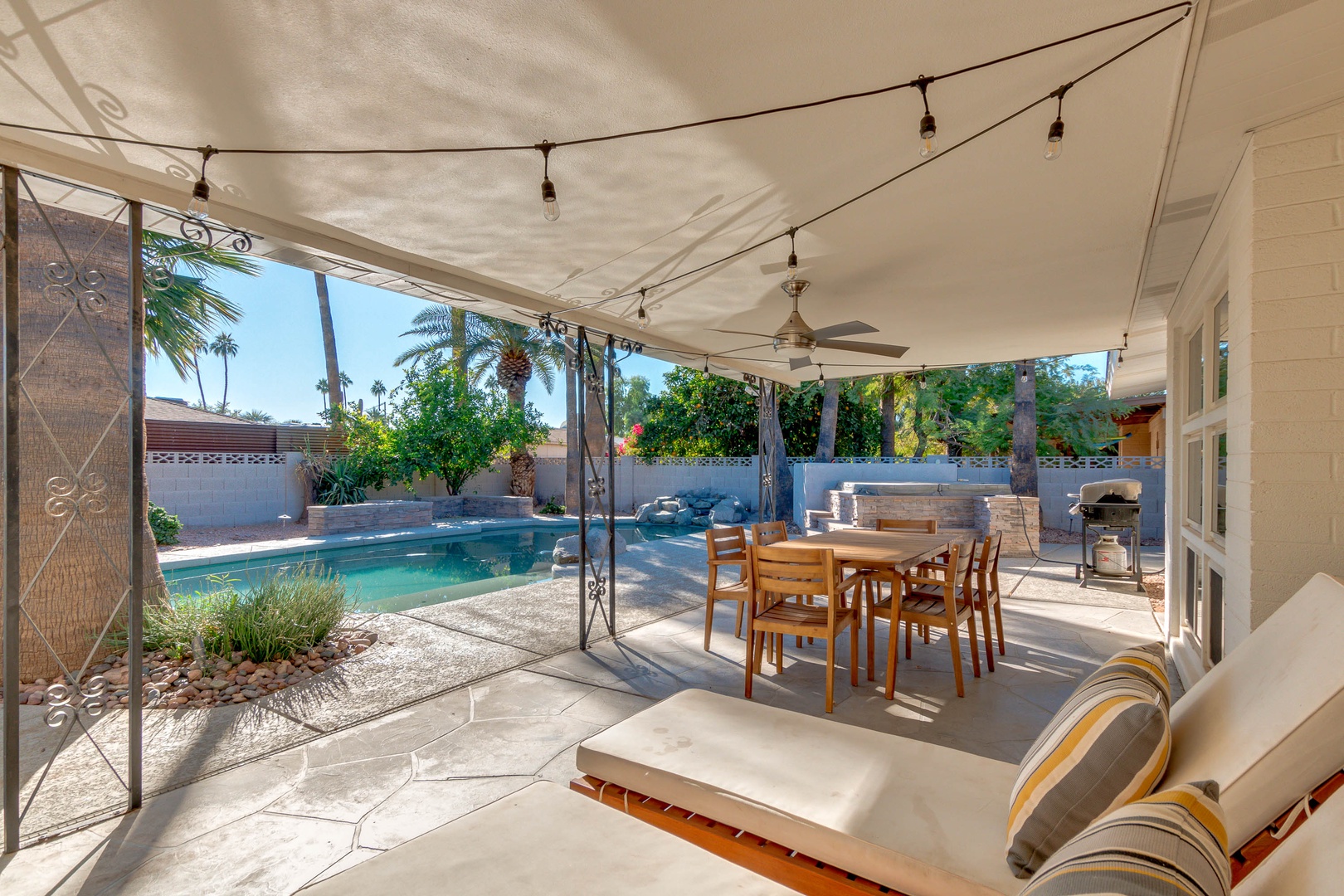 Spacious covered patio with loungers and table. Pool and hot tub in the back.