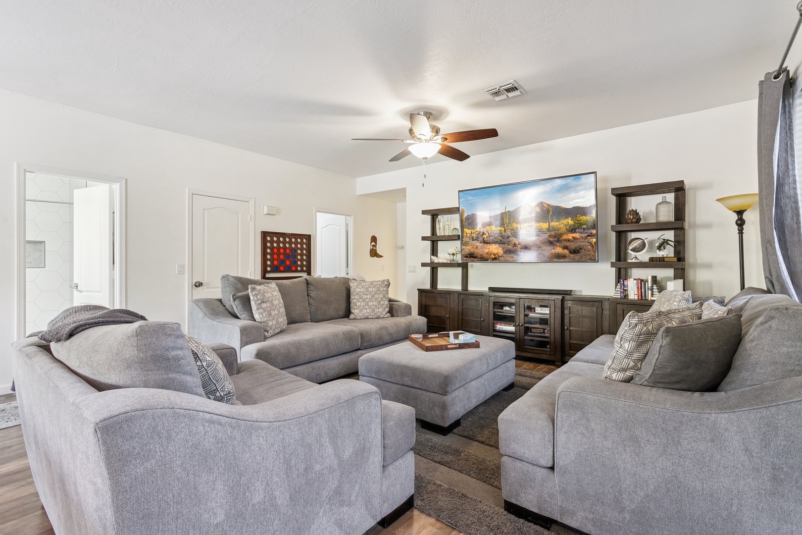 Relax in your spacious living room with plush gray seating, entertainment center, and desert views on the big screen.
