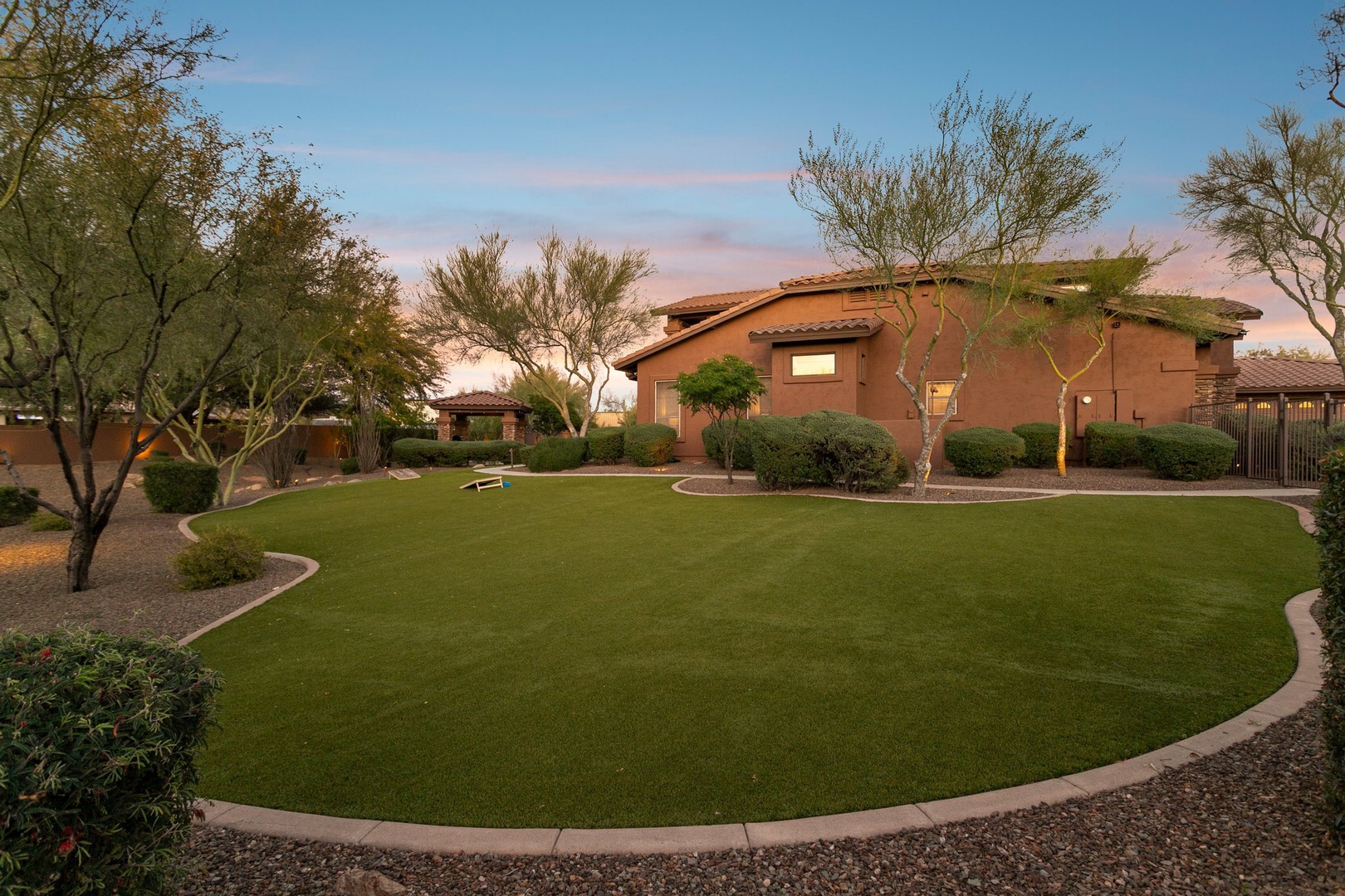 Desert oasis property featuring manicured lawns and native landscaping beneath dramatic southwestern skies.