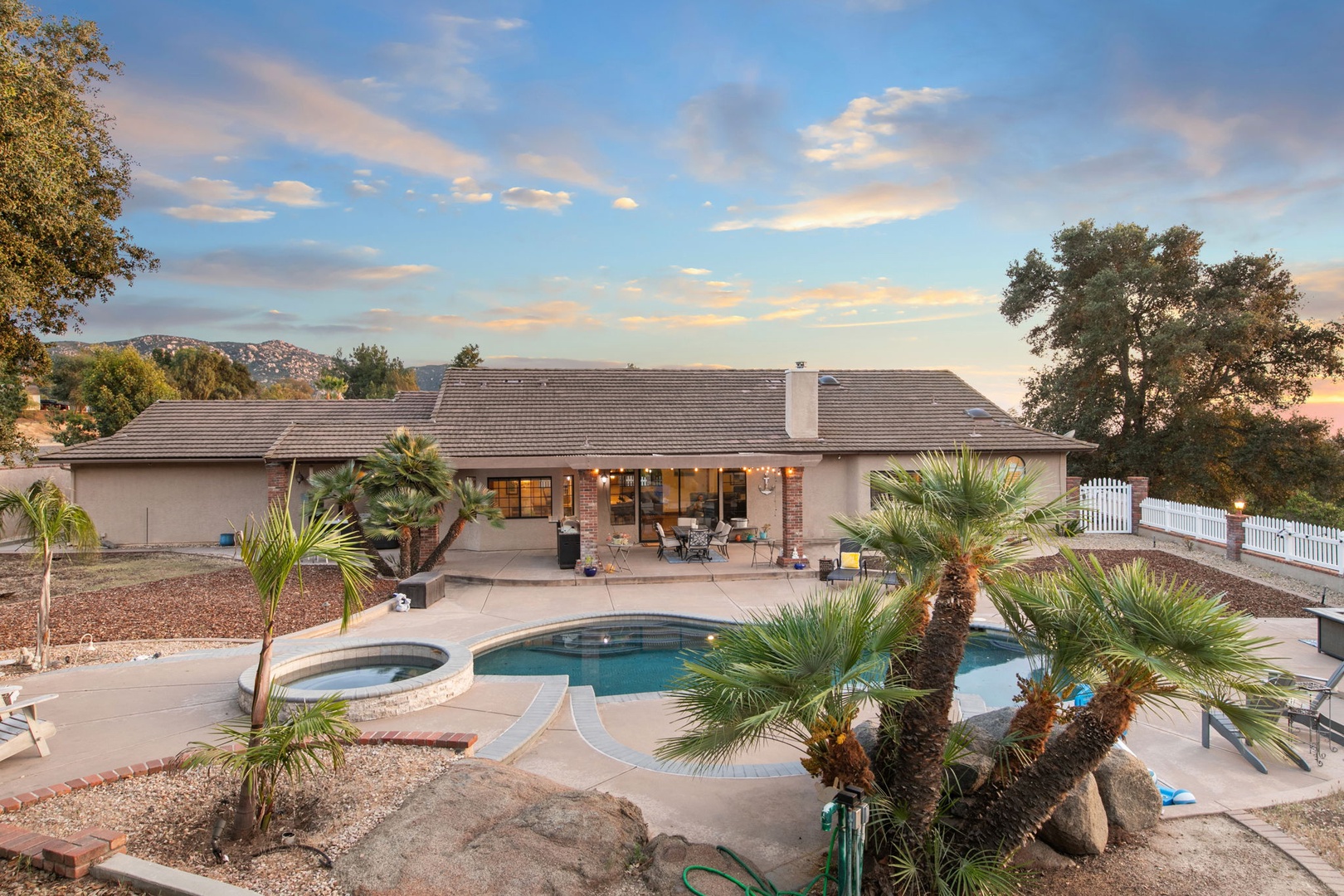 Desert oasis featuring a sparkling pool and spa surrounded by mature palm trees.