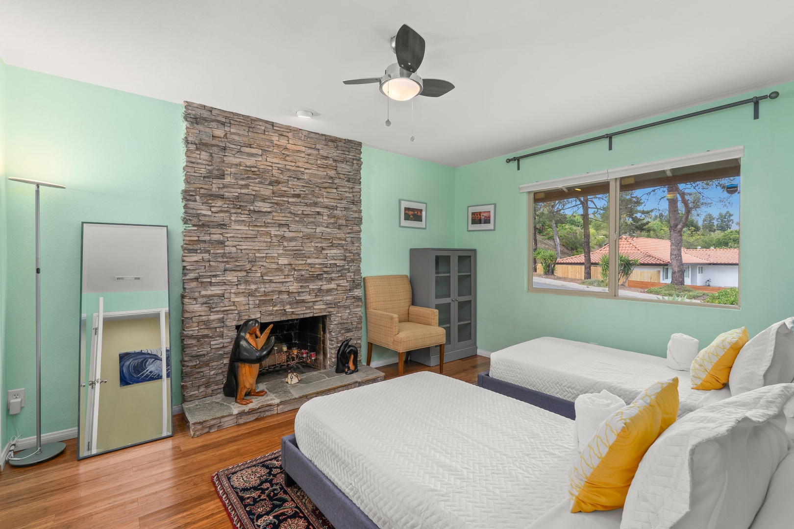Unwind in your cozy retreat with twin beds, a warming stone fireplace, and peaceful garden views through large windows.