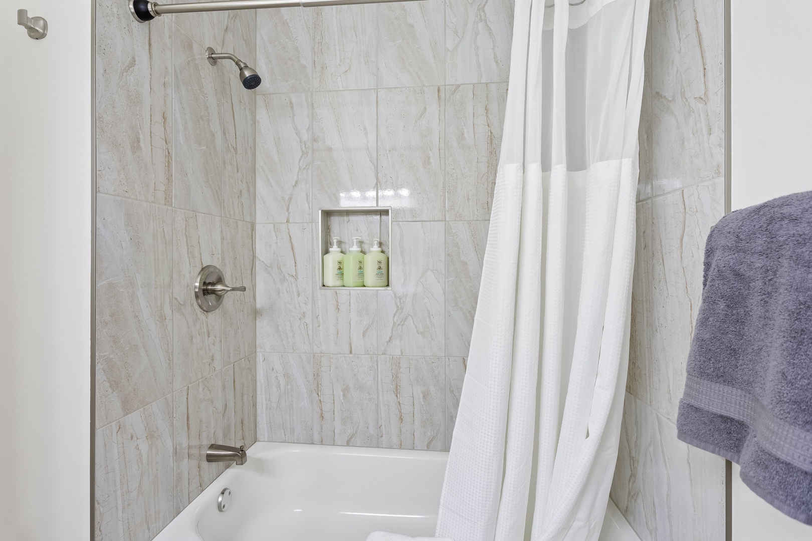 Step into your fresh, modern bathroom with marble-inspired tile, a walk-in tub-shower combo, and plush towels waiting for you.