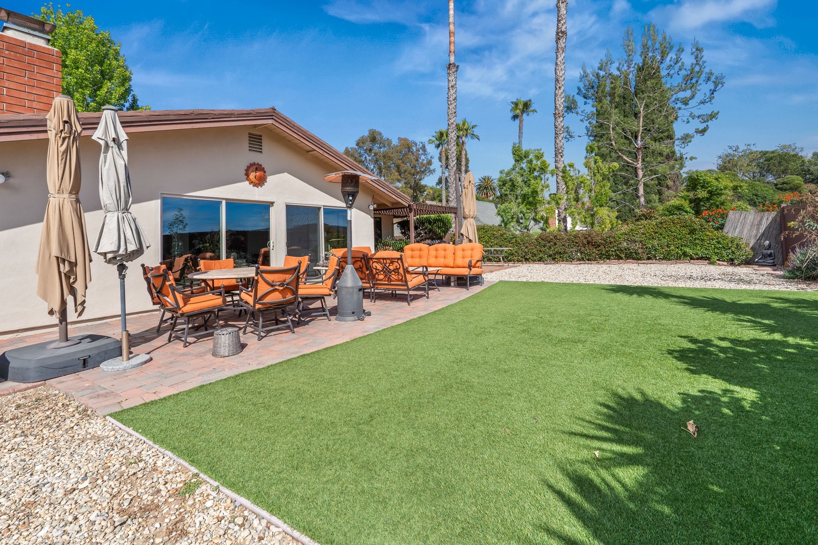 Relax in your private backyard oasis with spacious lawn, covered patio seating, and tropical palm trees creating the perfect outdoor retreat.