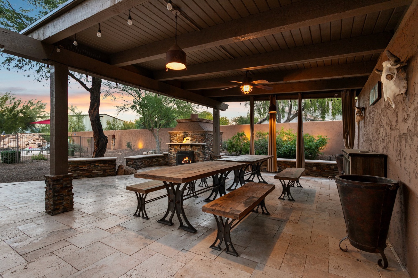 Gather around your private covered patio featuring rustic dining space, stone fireplace, and BBQ area - perfect for memorable evenings under ambient lighting.