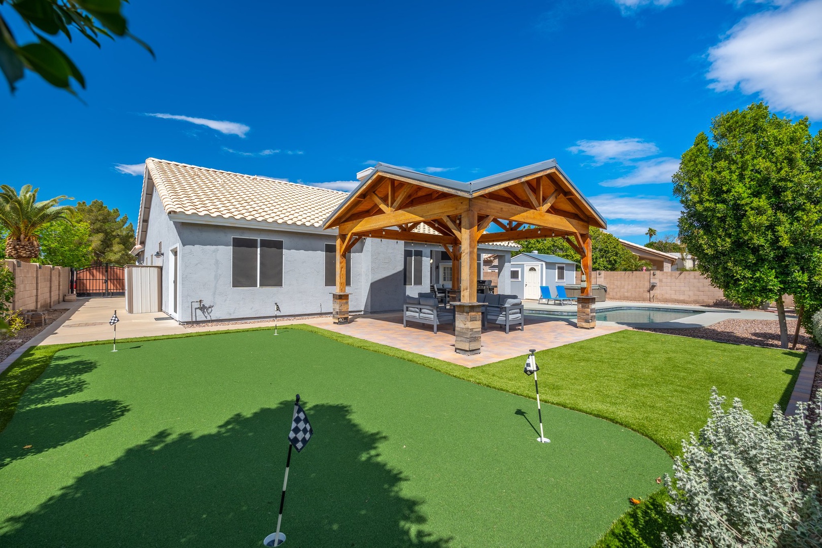 Spacious backyard retreat featuring a private putting green, covered patio with comfortable seating, and sparkling pool. Perfect for warm Arizona days and outdoor gatherings.