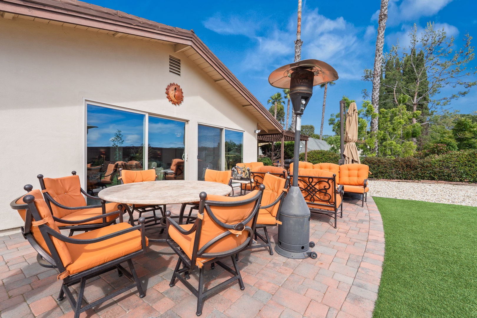 Relax on your private patio with plush orange seating and outdoor heater, perfect for year-round comfort under sunny desert skies.