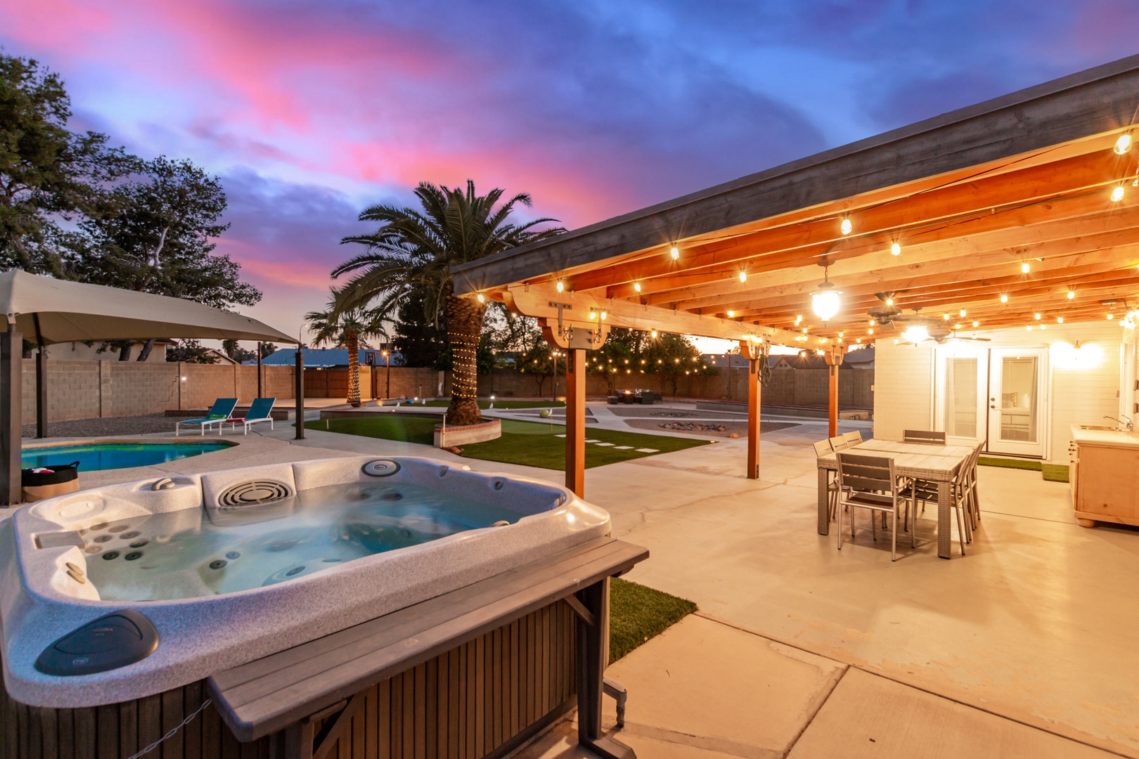 Backyard Oasis with a hot tub, pool, putting greens, lounge area with fire pit and more!