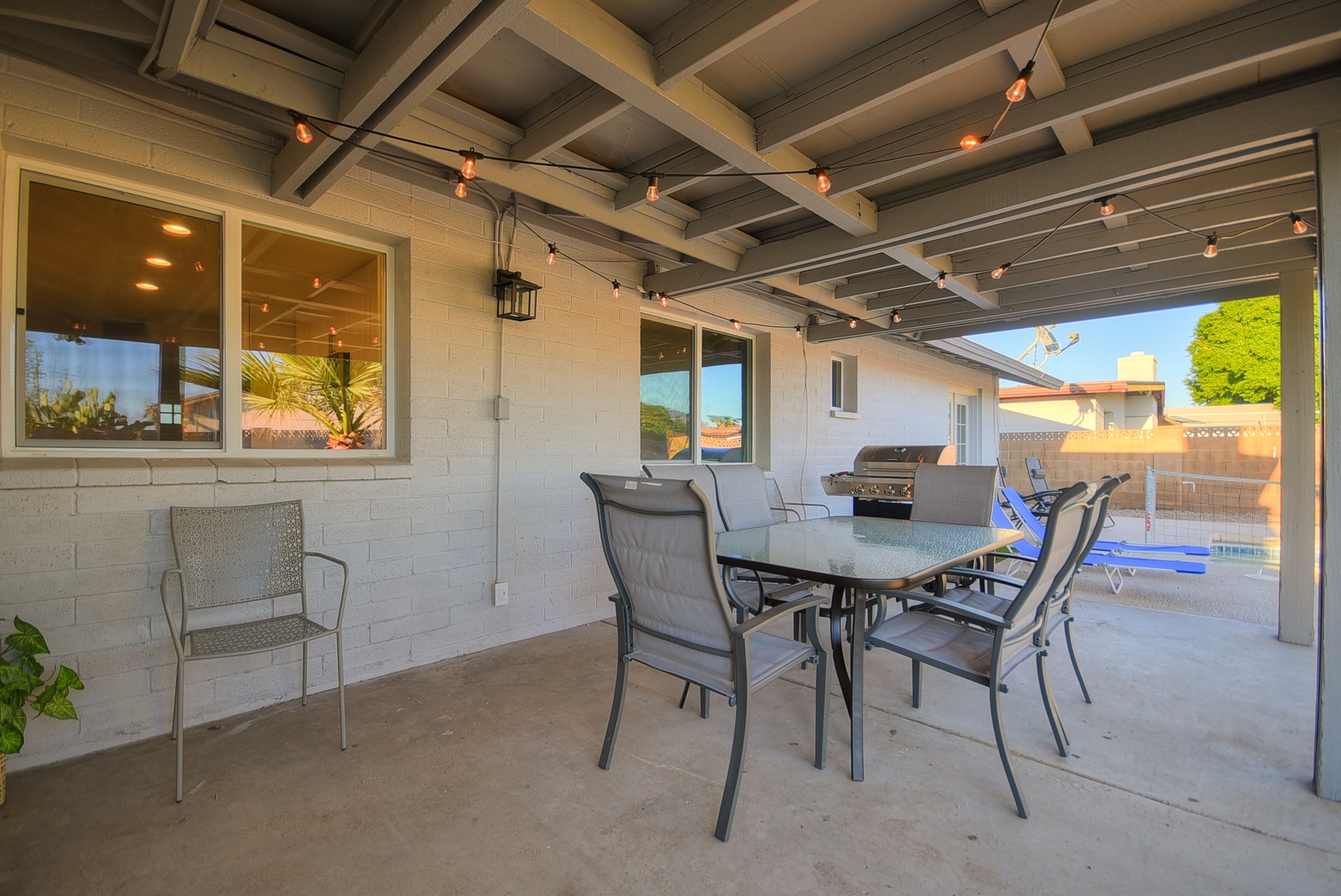 Covered patio area with outdoor dining table and bbq grill