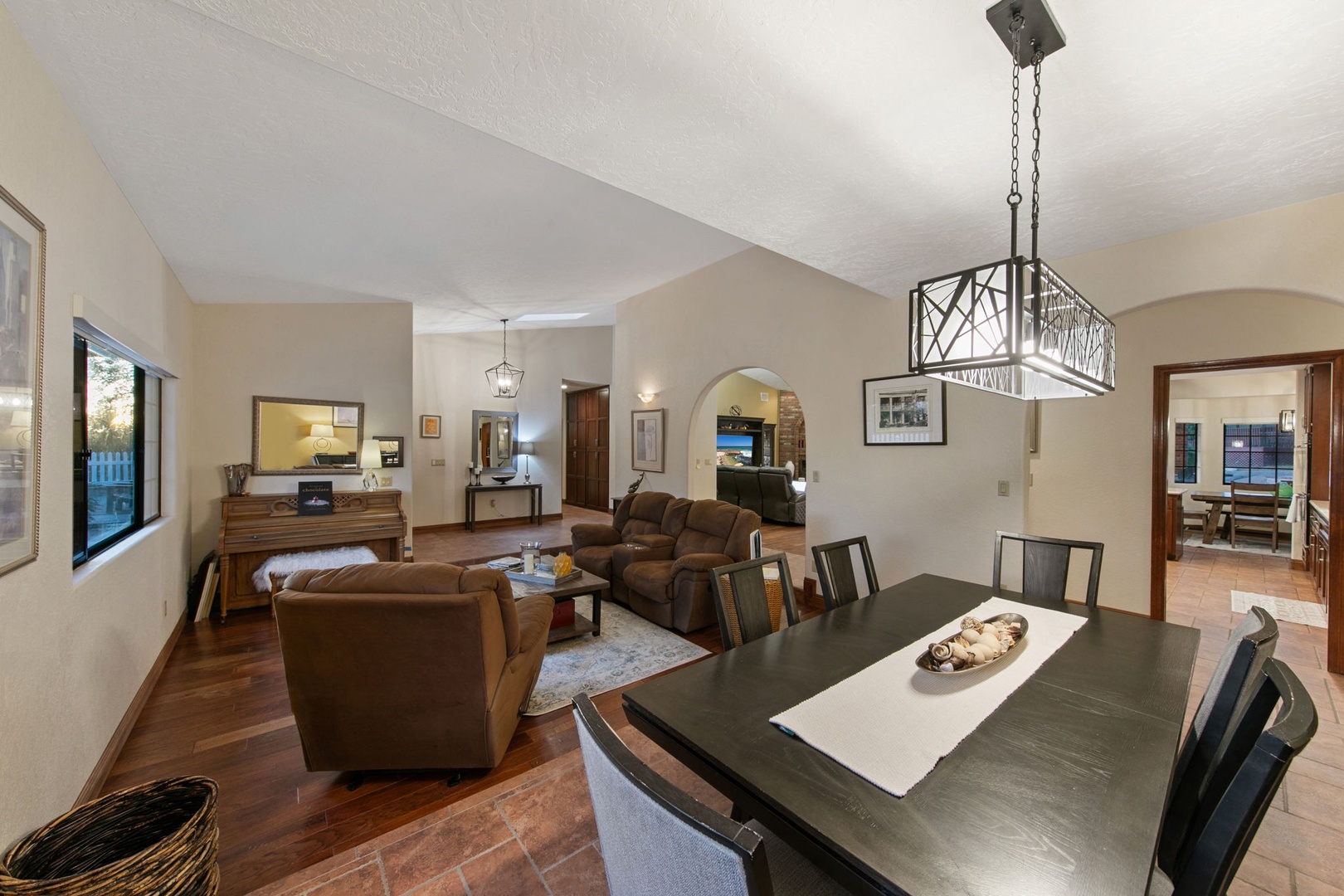 Relax in your spacious open-plan living area with leather seating, elegant dining table, and modern chandelier creating the perfect atmosphere for memorable evenings.