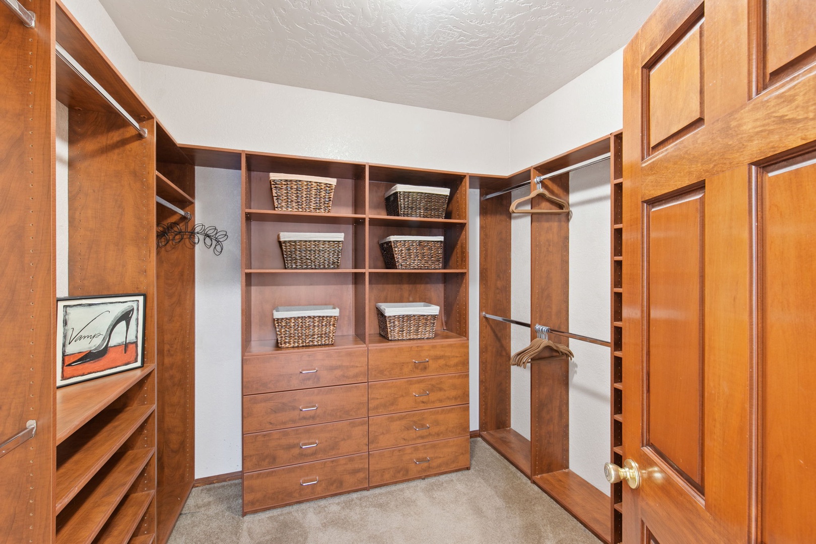 Your spacious walk-in closet features rich wood shelving, elegant wicker baskets, and abundant hanging space for all your belongings.