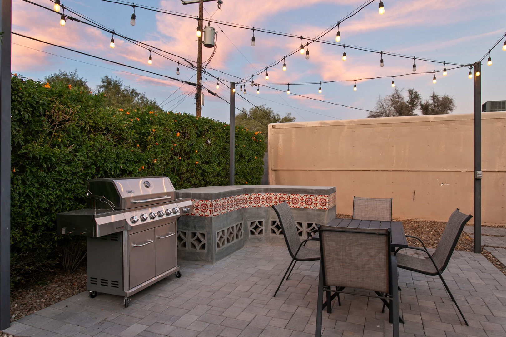 Your private outdoor BBQ area awaits with a premium gas grill and dining space, all lit by twinkling string lights for magical evening gatherings.
