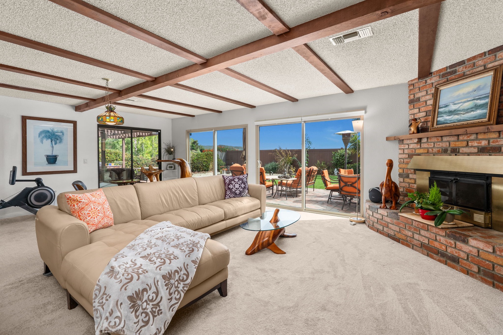 Relax in your bright living room where exposed beams and a brick fireplace create warmth while patio doors open to outdoor dining.