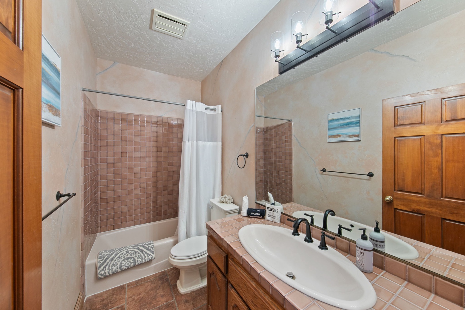 Refresh in your private bathroom featuring a relaxing tub-shower combo, tile accents, and thoughtful amenities for your comfort.
