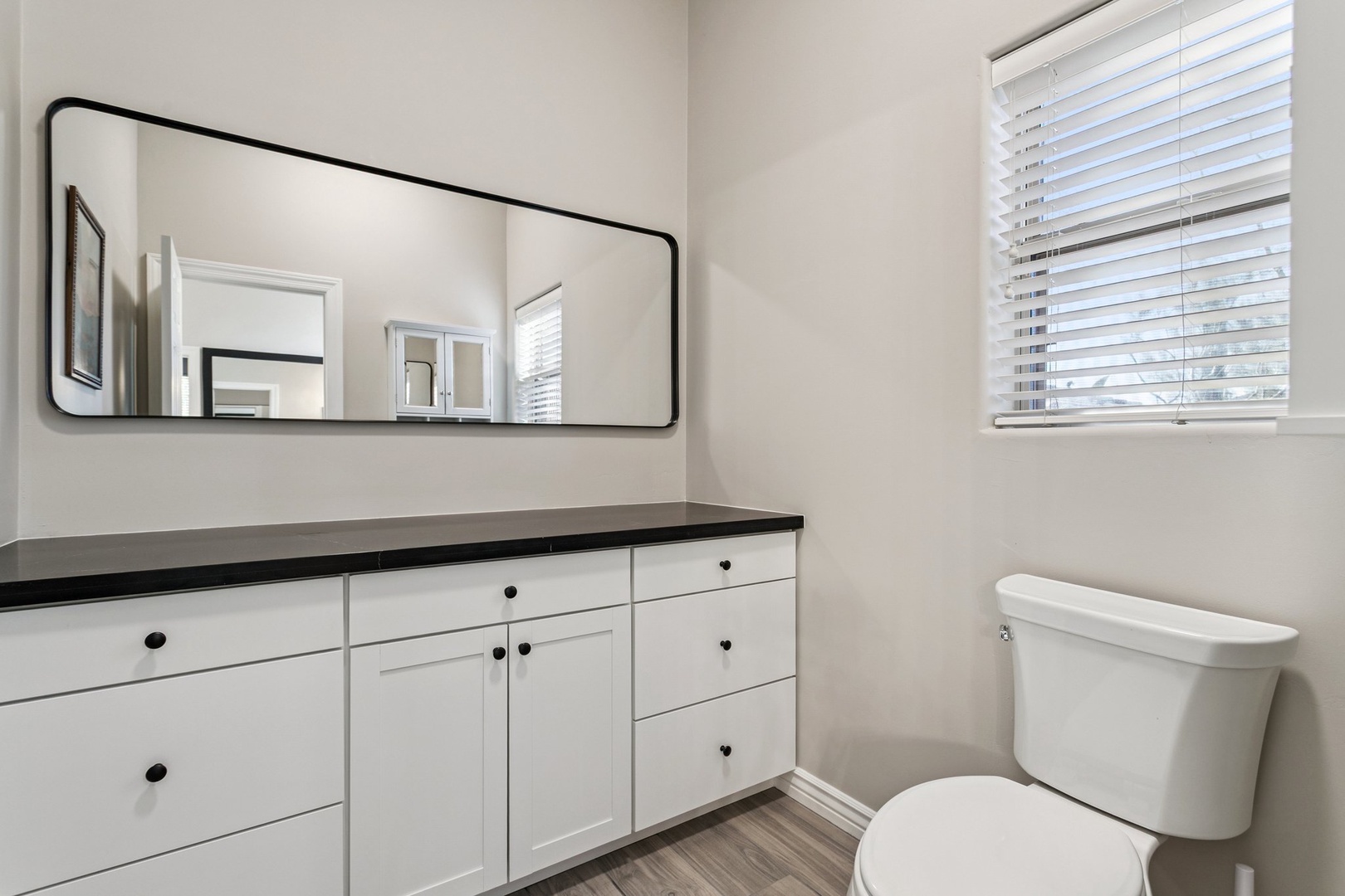 Freshen up in your bright, modern bathroom featuring a sleek vanity with ample storage and natural light from the window.