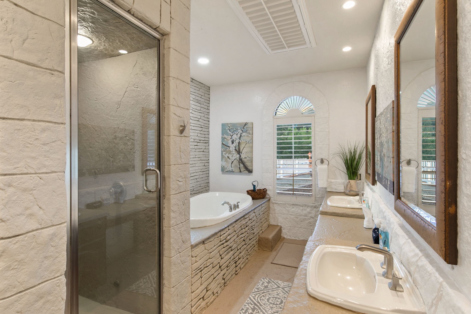 Unwind in your luxurious spa-like retreat featuring a soaking tub, spacious walk-in shower, and elegant stone accents throughout. (Left sink out of order))