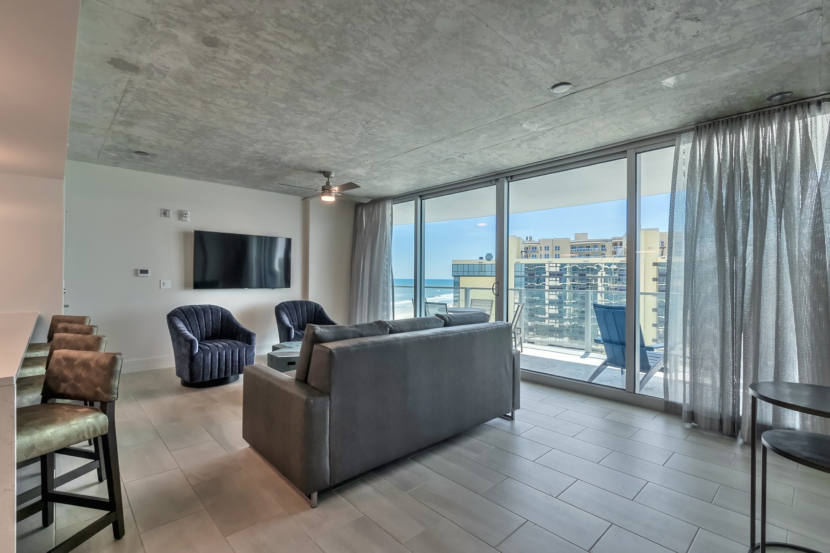 Cityscape & Seaside Vibes: Relax in the Stylish Living Area with Urban and Ocean Backdrop