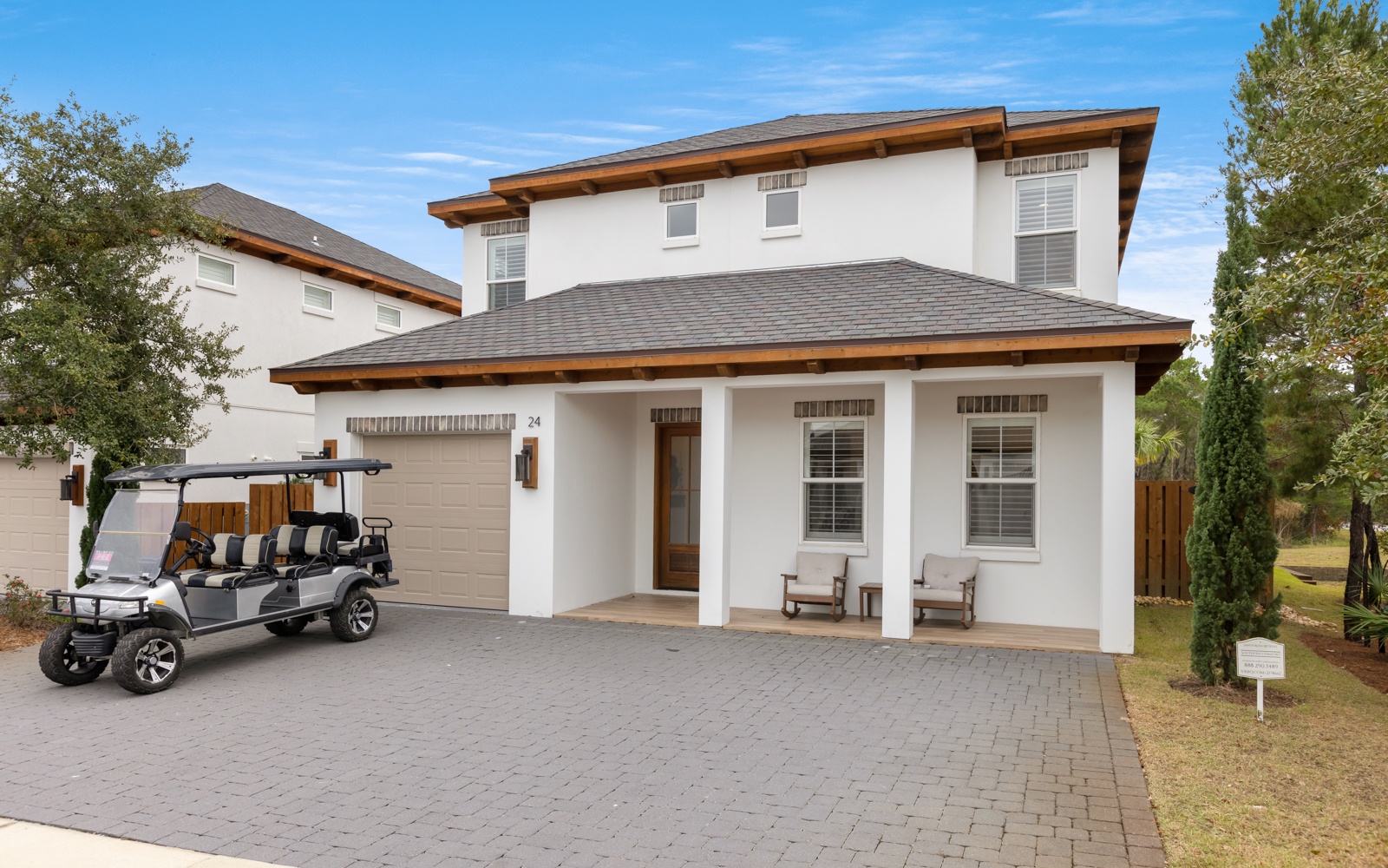 Modern two-story vacation home with covered front porch and golf cart parking in a peaceful residential setting.