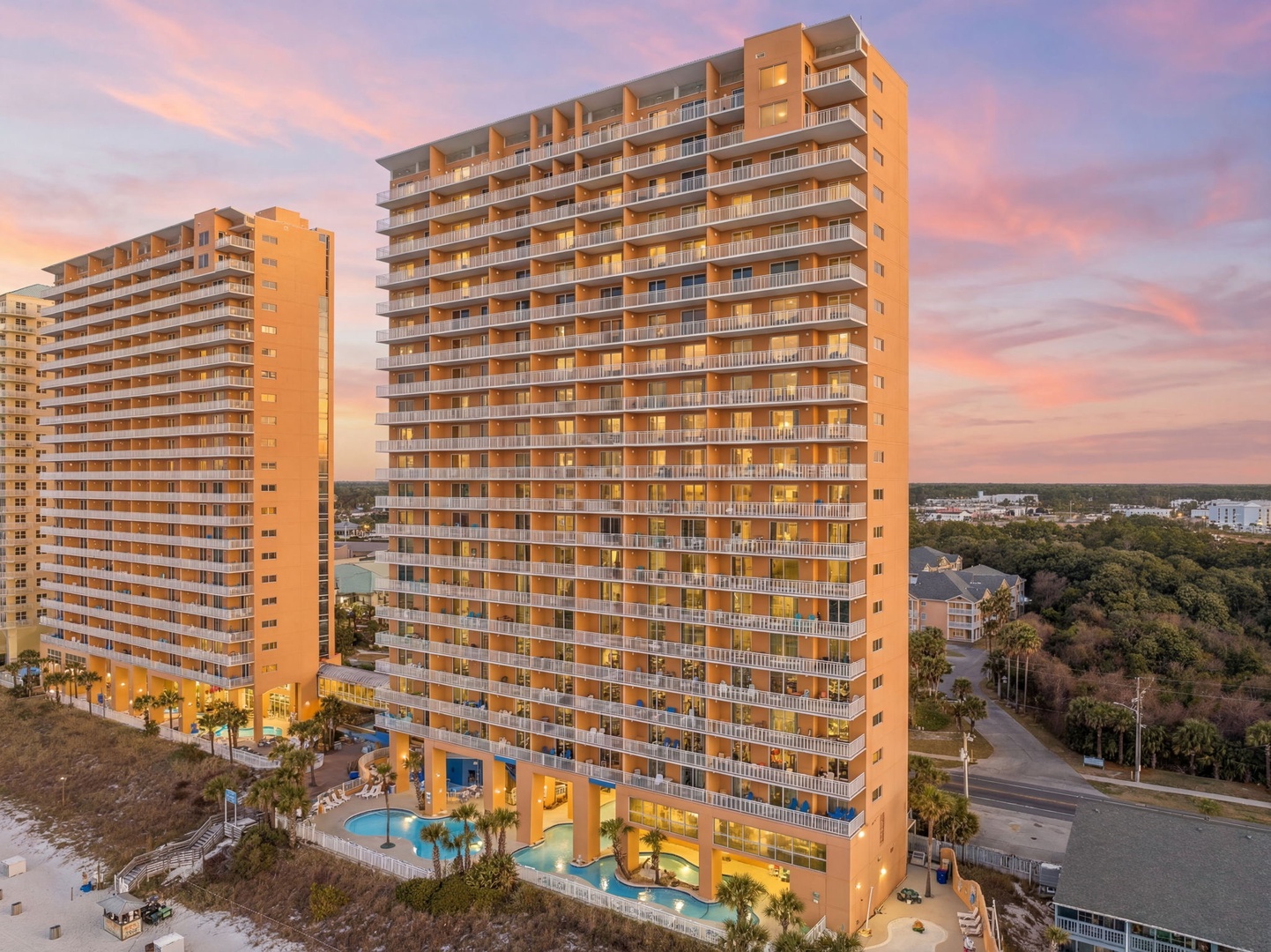 Stunning beachfront towers rise majestically against a golden sunset sky, offering a perfect coastal retreat setting.