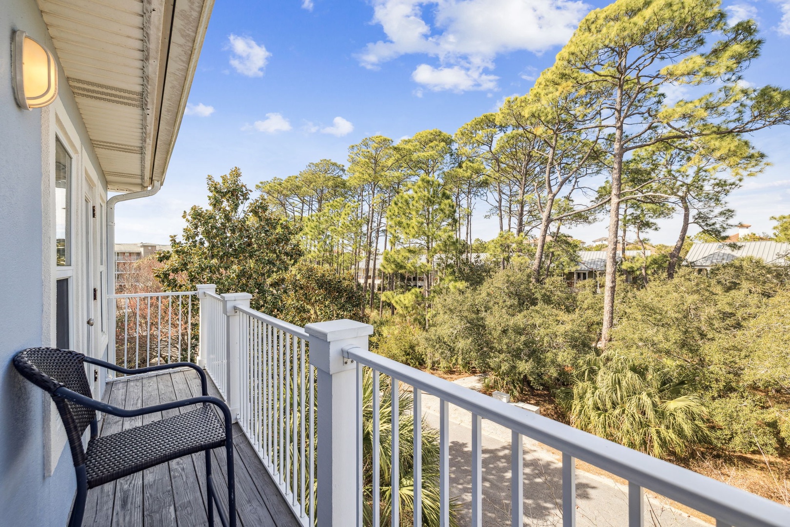 Step onto your private balcony where two comfy chairs await your morning coffee ritual, surrounded by towering pines and endless blue skies.