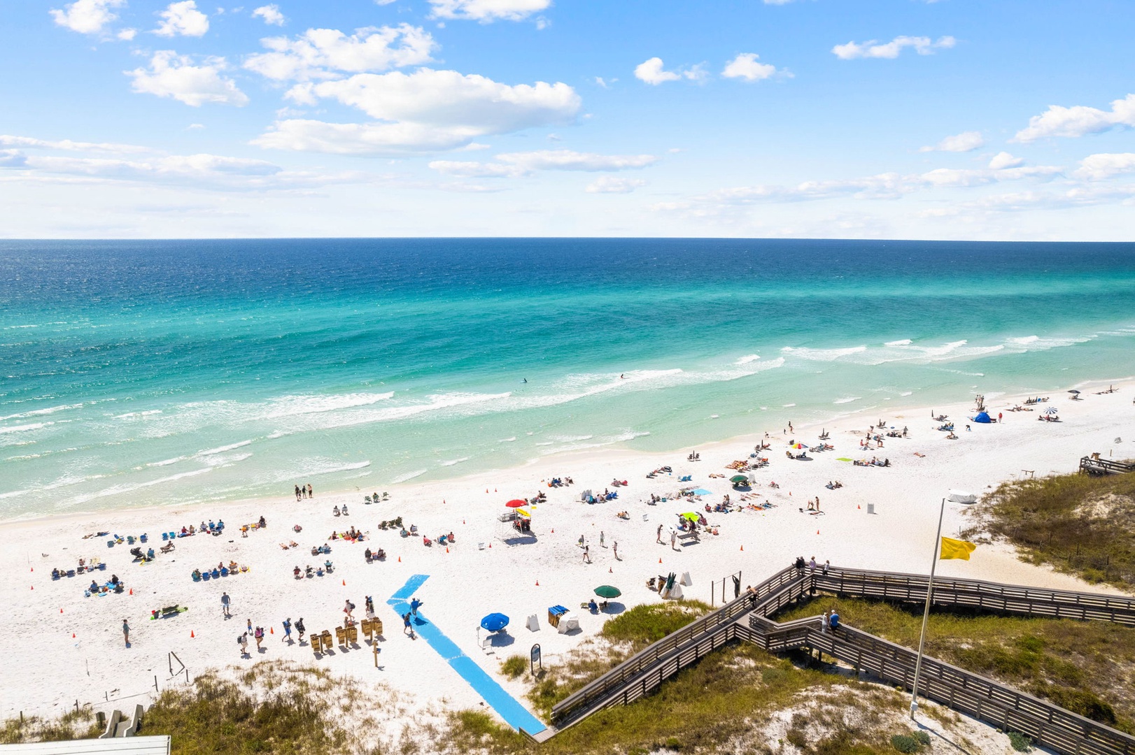 Pristine white sand beach with crystal-clear turquoise waters stretching to the horizon, featuring convenient boardwalk access.