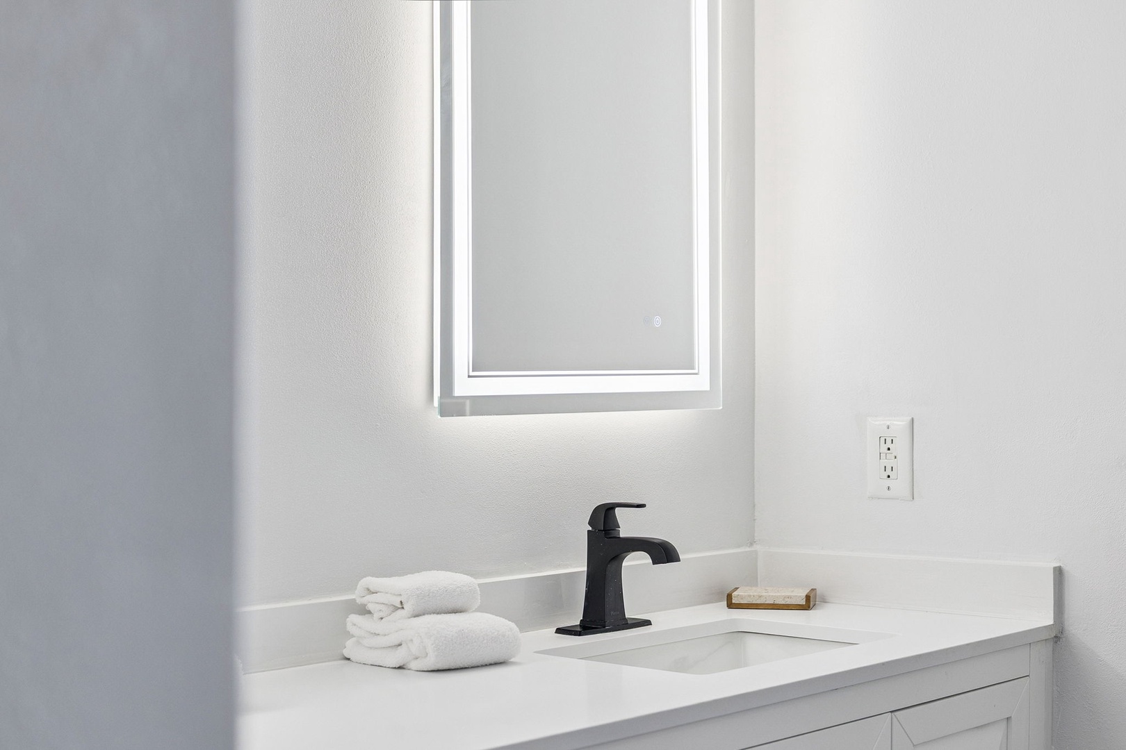 Pamper yourself in this pristine bathroom with LED-lit mirror, elegant fixtures, and fluffy towels awaiting your arrival.