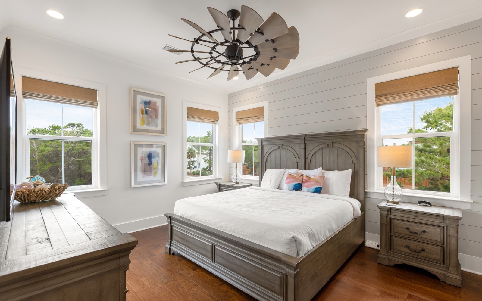 Rest peacefully in your serene bedroom featuring shiplap walls, elegant furnishings, and natural light flowing through multiple windows.