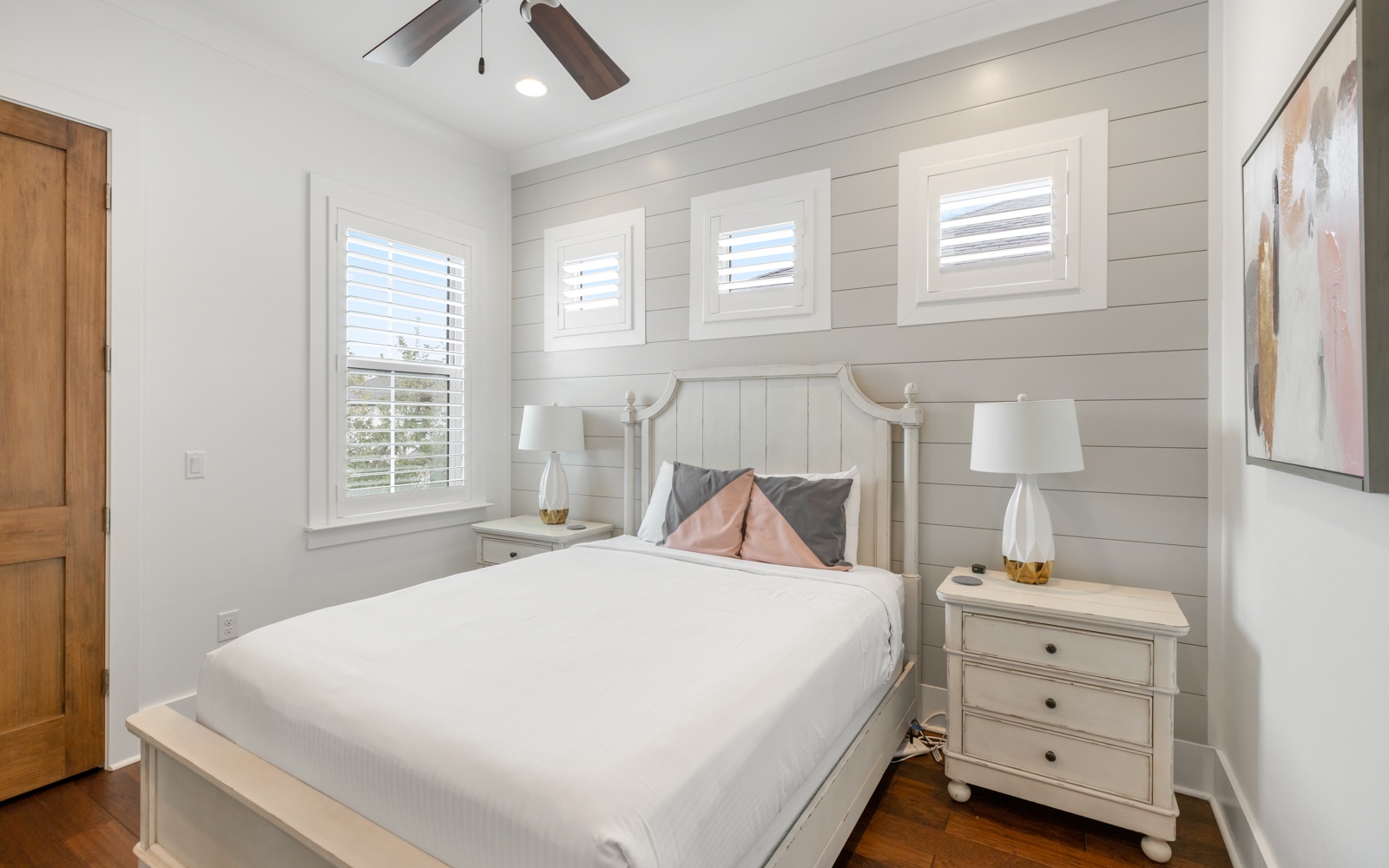 Sink into crisp white linens in this serene bedroom, where coastal-style shiplap walls and soft natural light create your perfect retreat.