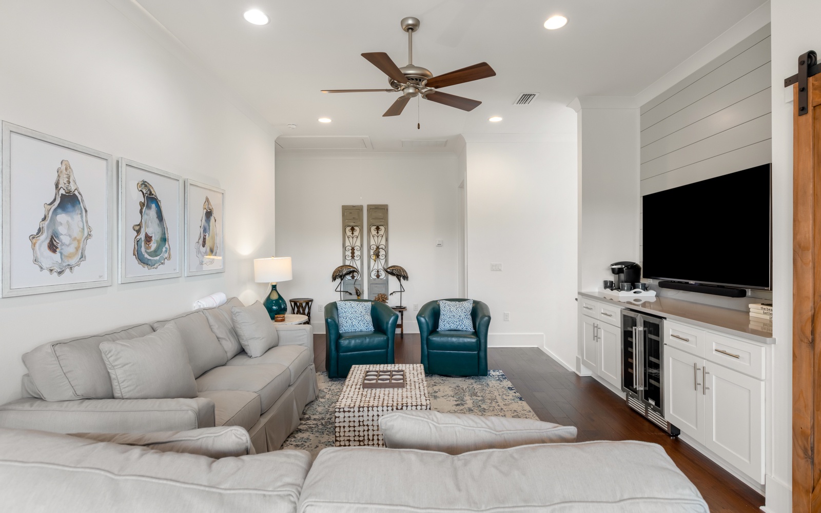 Unwind in your stylish living room featuring plush seating, coastal artwork, and built-in entertainment center for perfect relaxation.