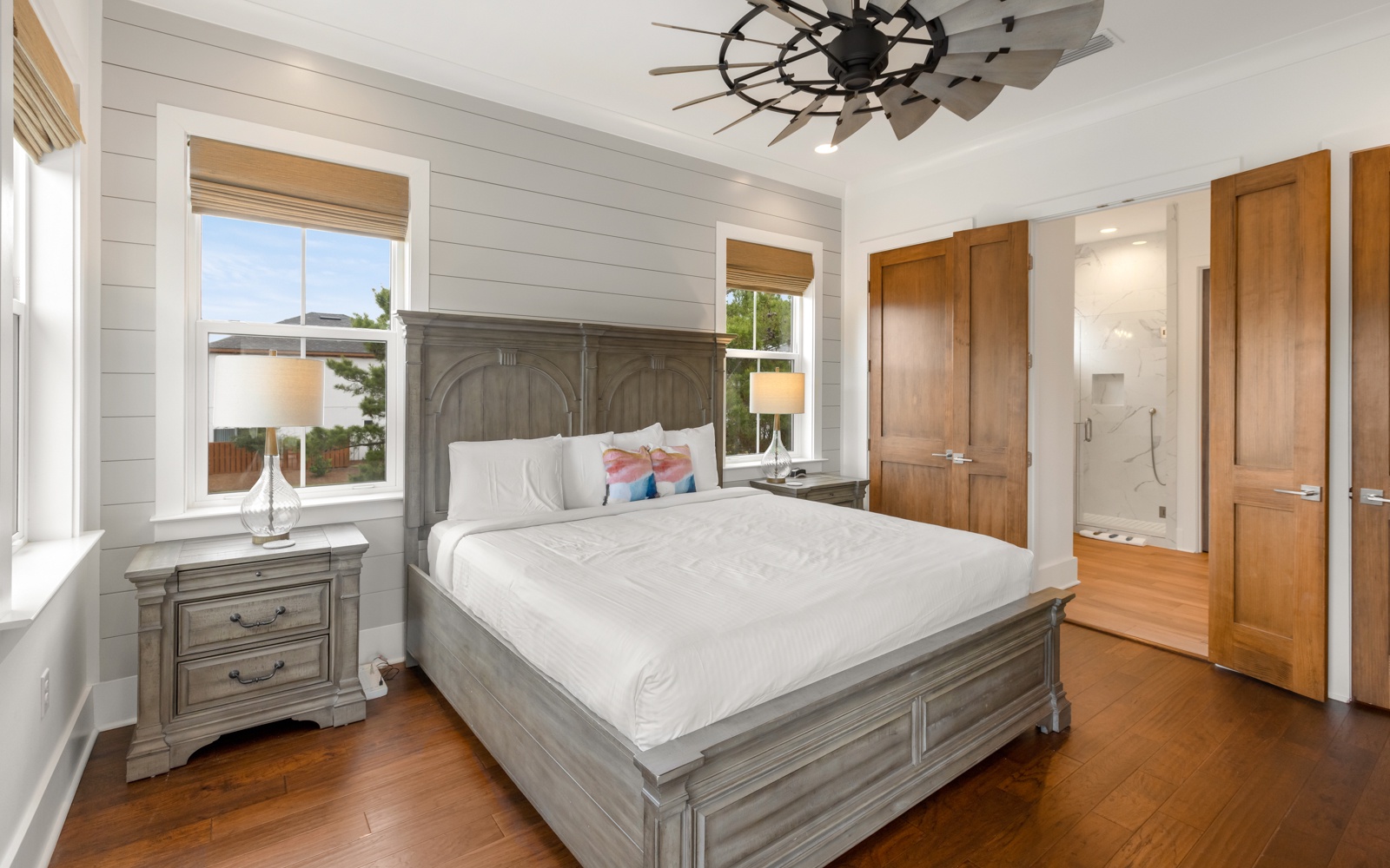 You'll love waking up in this serene bedroom with crisp linens, warm wood floors, and natural light streaming through bamboo shades.