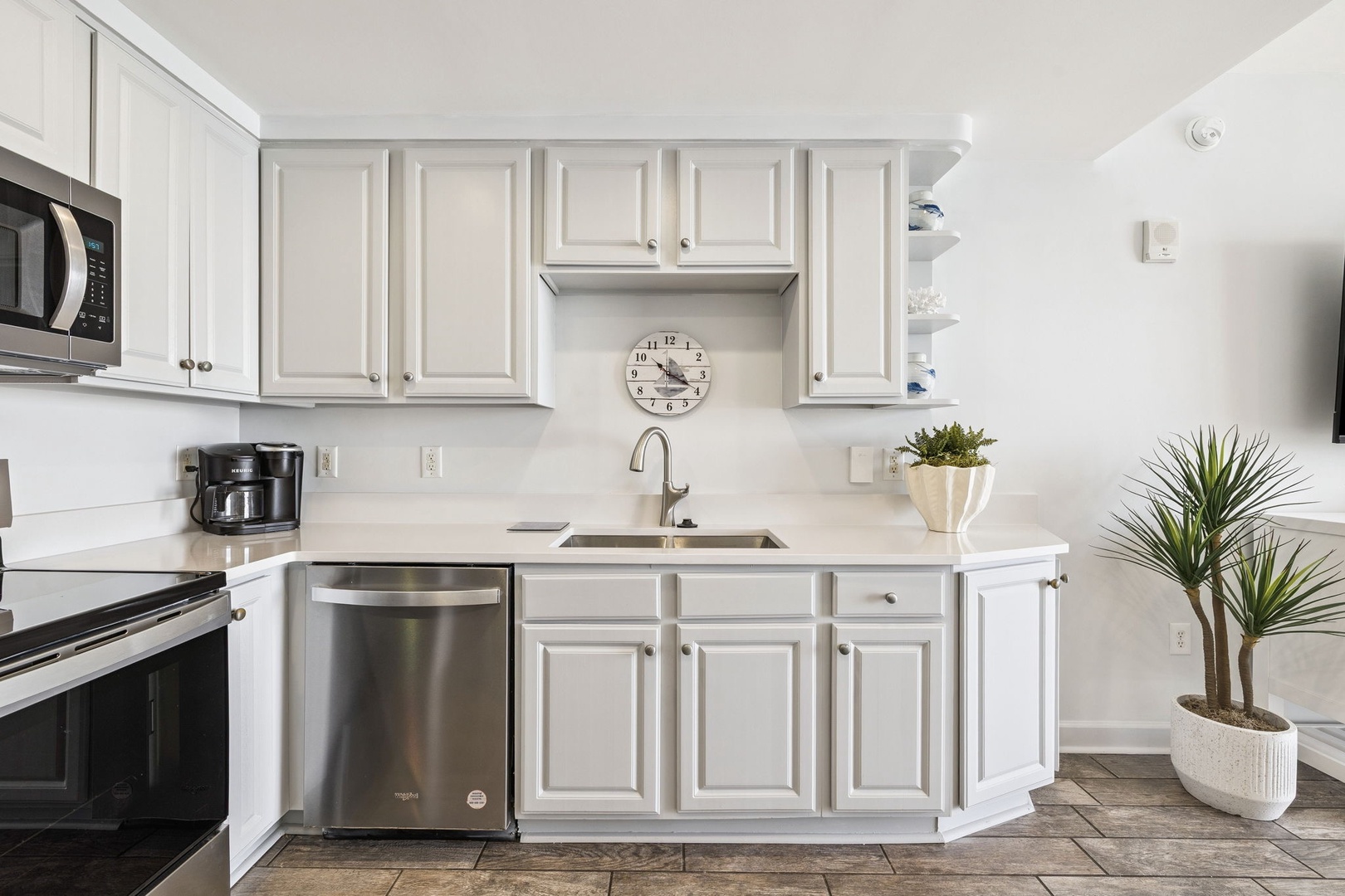 Your modern kitchen awaits with crisp white cabinets, stainless steel appliances, and warm wood-look floors creating the perfect space for morning coffee.