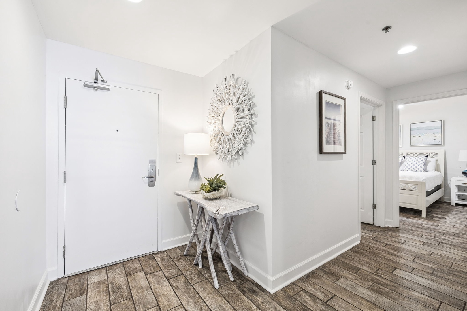 Step into your bright, welcoming entryway with elegant decor and warm wood floors leading to your comfortable bedroom.