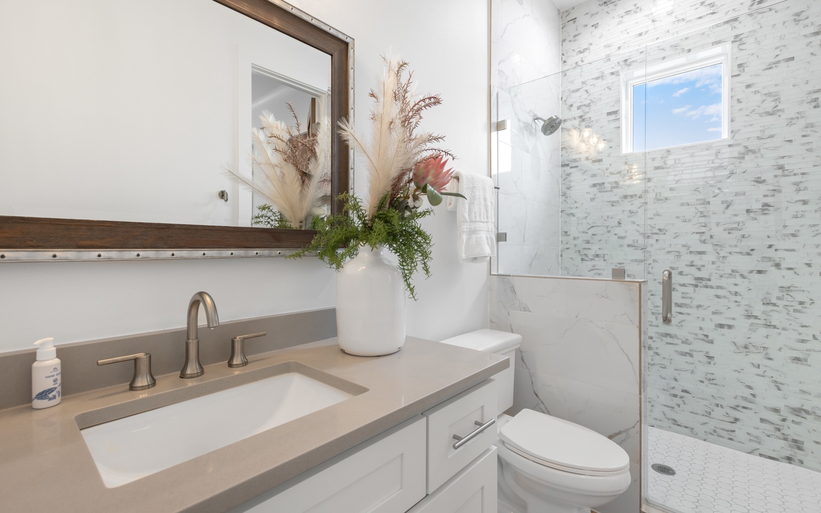 Step into your private spa-like retreat with marble-tiled shower and elegant vanity adorned with fresh florals.