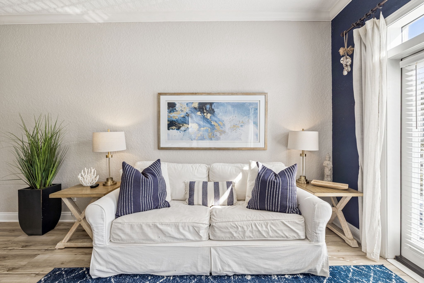 Sink into this inviting white sofa with navy accents, where coastal charm meets comfort in your bright, stylish living space.