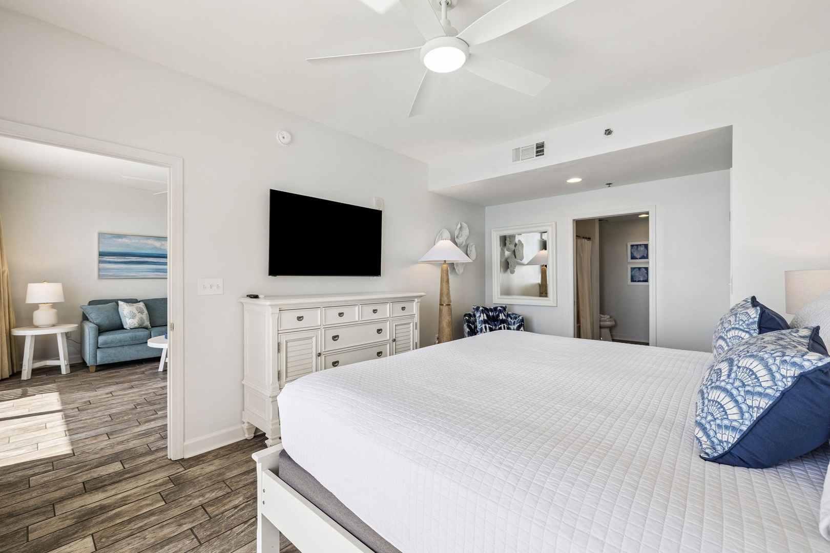 Relax in your spacious bedroom with coastal-inspired decor, crisp white linens, and modern entertainment center for cozy evenings.